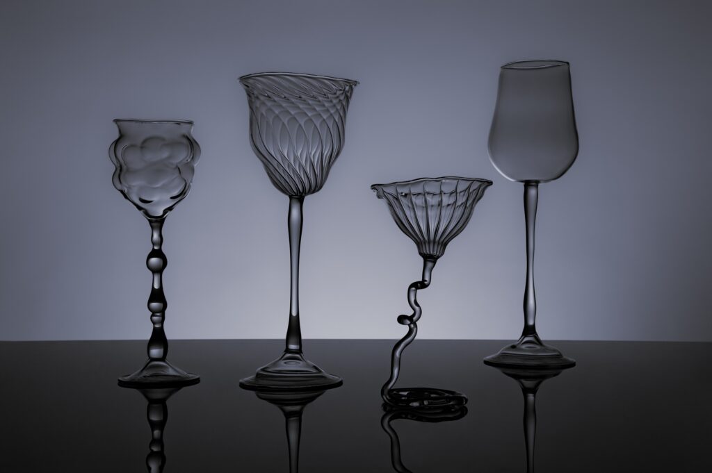 Verre à pieds contemporain, soufflé au chalumeau en verre borosilicate, sur fond noir.