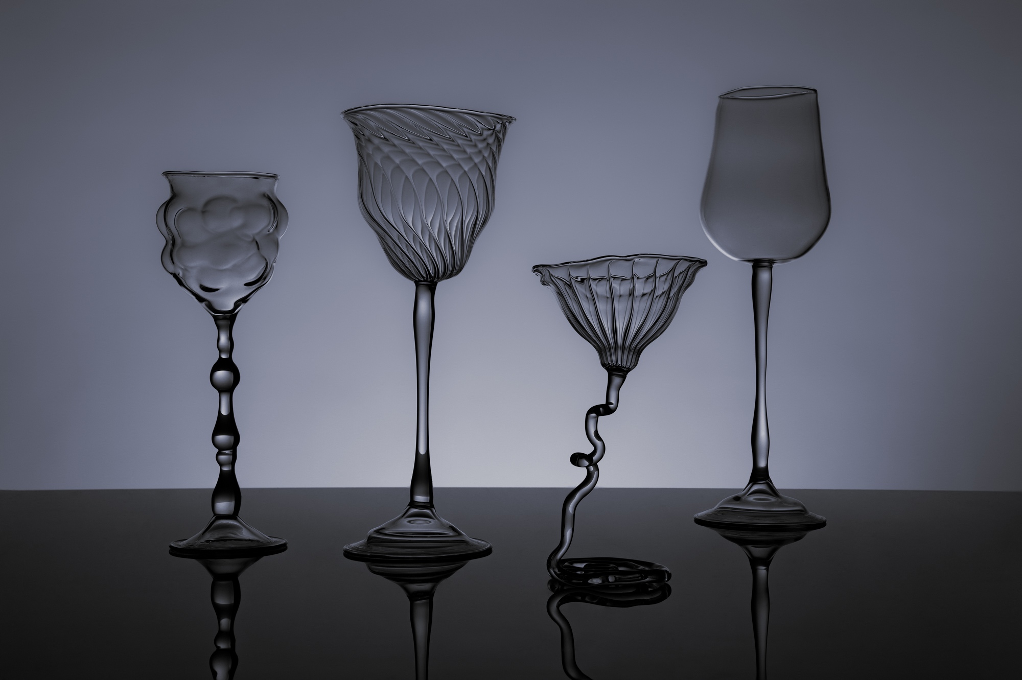 Verre à pieds contemporain, soufflé au chalumeau en verre borosilicate, sur fond noir.