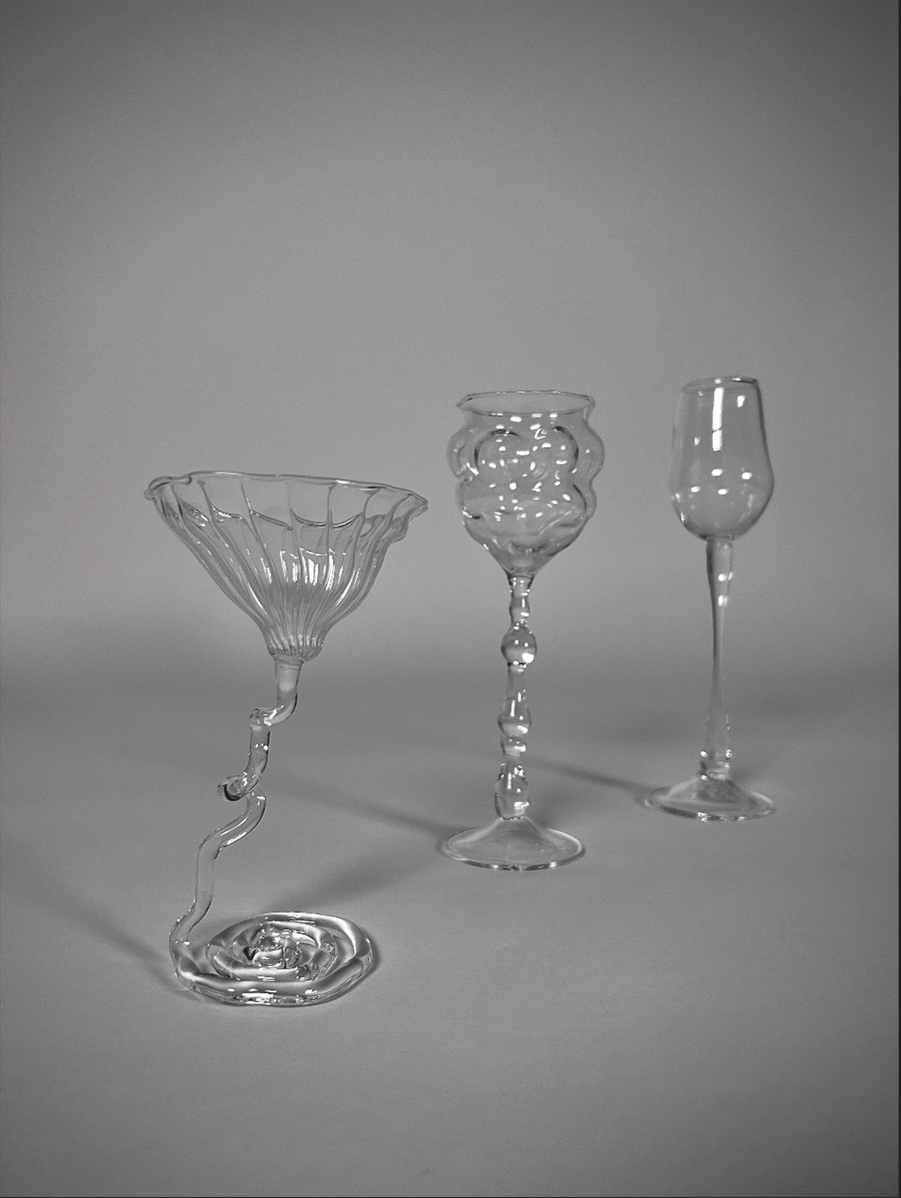 Verre à pieds contemporain, soufflé au chalumeau en verre borosilicate, sur fond gris.