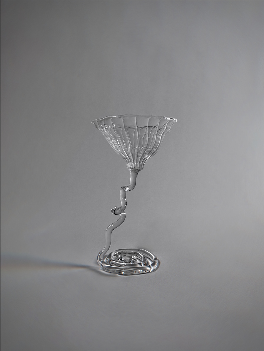 Verre à pied contemporain, soufflé au chalumeau en verre borosilicate, sur fond gris.