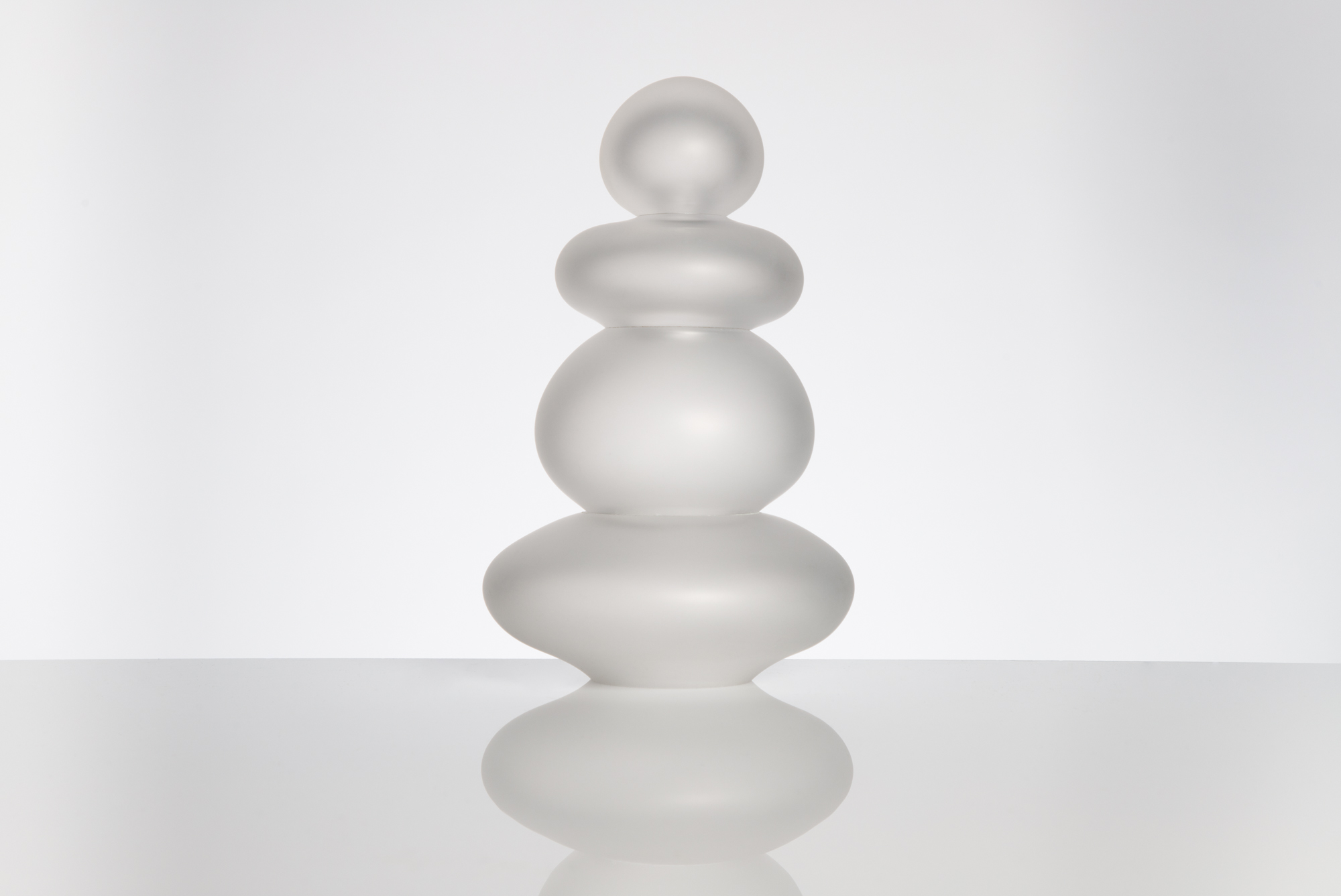 Lampe de table en verre soufflé transparent artisanale sur un fond blanc, vue de face.