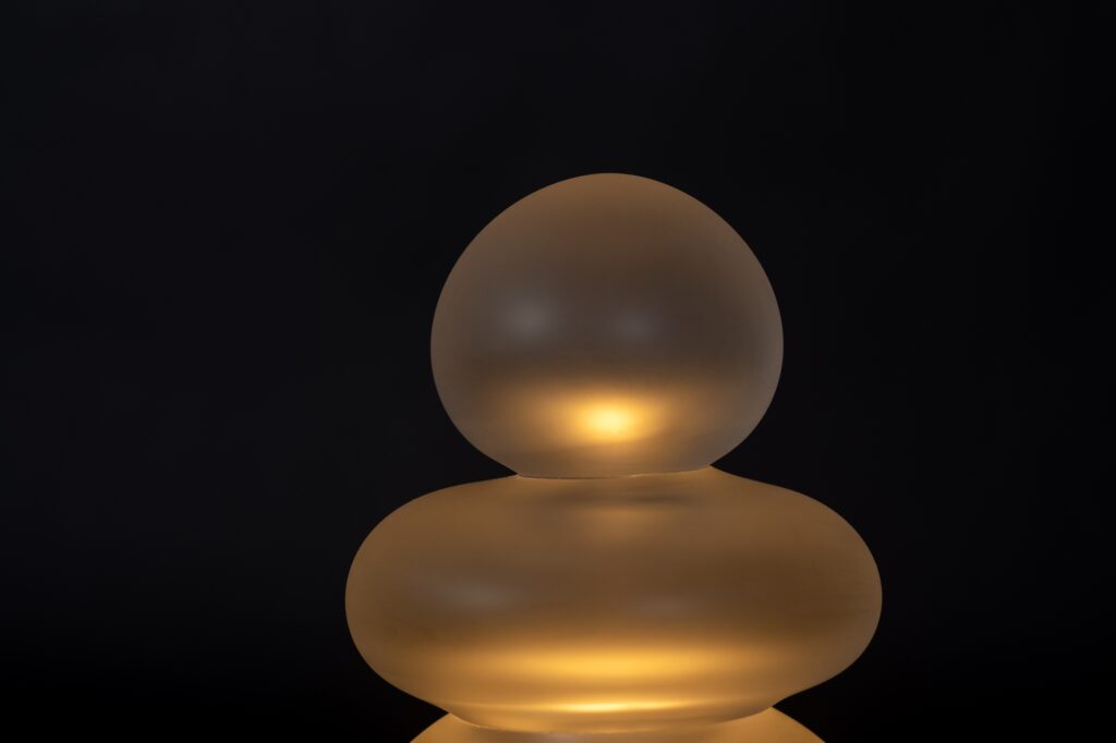 Lampe de table en verre soufflé transparent artisanale sur un fond noir, vue de proche.