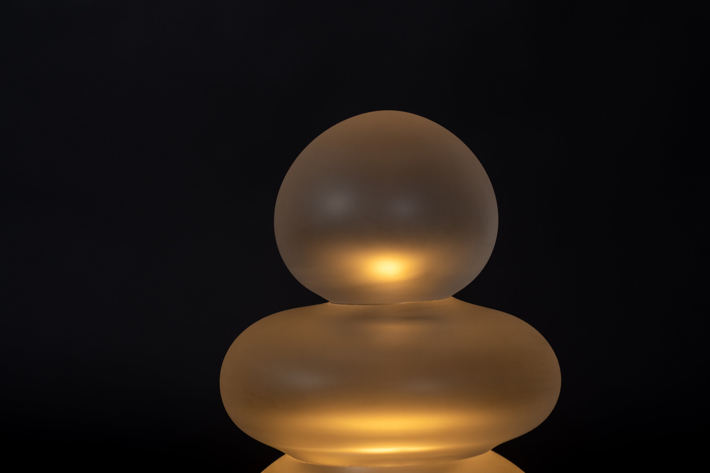 Lampe de table en verre soufflé transparent artisanale sur un fond noir, vue de proche.